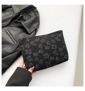 Detail shot of black floral hand clutch with embossed 3D flower texture on fabric