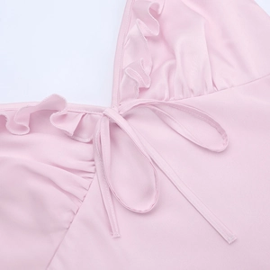 Detail of pink slip dress showing delicate ruffles and silk-like bow tie on the V-neckline