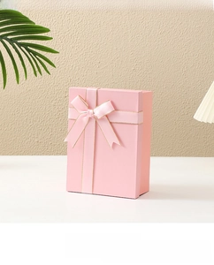 Close-up of pink rectangular gift box with gold-edged satin ribbon and bow detailing