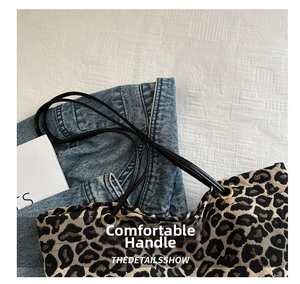 Detail of leopard print tote bag featuring textured fabric and sleek black handles