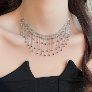 Detail of silver tassel necklace with multiple fine chains and spherical charms on model