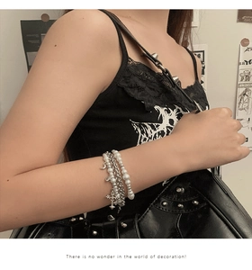 Détail d'un bracelet Y2K multicouche avec perles, pendentifs croix et lune porté au poignet