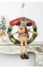 Christmas wreath with plush reindeer and 'Let it snow' sign on a white fireplace