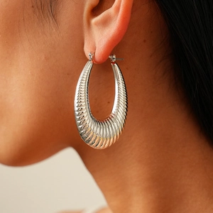 Polished silver textured oval hoop earrings with a chunky minimalist ripple pattern design
