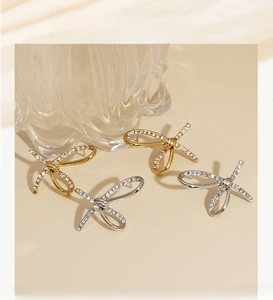 Close-up of bow knot earrings in gold and silver finish with sparkling zircon stones