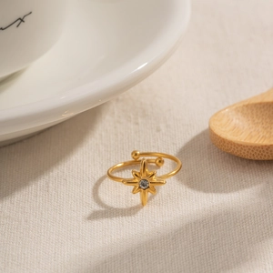 Elegant gold octagonal star open ring with a sparkling zircon on beige textured fabric