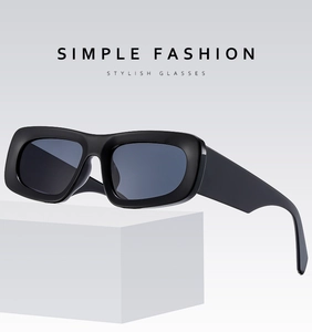 Detail view of black chunky rectangle sunglasses on a minimalist white platform
