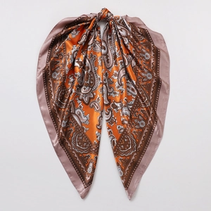 Detailed view of paisley silk scarf texture with bright orange and brown patterns