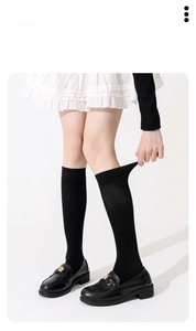 Detail showing the elastic spandex fabric and high-density knit of black knee-high socks