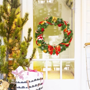 Détail d'une couronne de Noël avec nœuds rouges et boules dorées sur une porte blanche