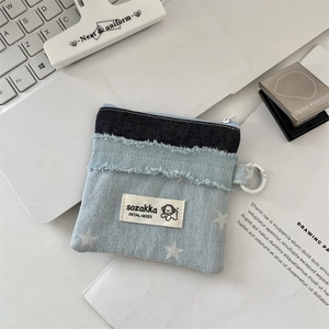 Detail einer Denim-Patchwork-Geldbörse mit Sternmuster und Reißverschluss auf weißem Tisch