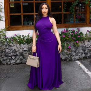Purple halter neck maxi dress with pleated waist and flowing skirt in outdoor setting
