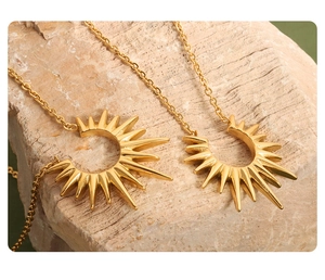 Macro detail of gold sunburst pendant necklaces layered on textured natural stone