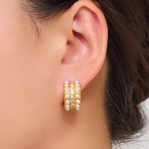 Elegant gold plated half-hoop earrings with pearls and crystals on a female model