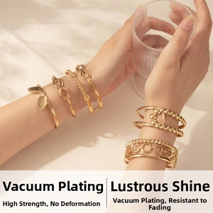 Macro detail of polished gold-plated infinity and geometric chain bracelets on wrist