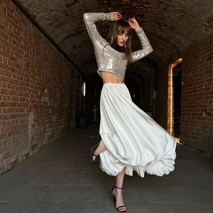 Detailweergave van de soepele witte plooirok en de korte top met lovertjes in een vintage tunnel