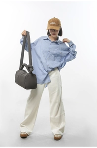 Deep grey quilted cylinder crossbody bag shown on a model with a casual outfit