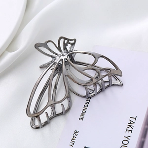 Elegant hollow butterfly hair claw clip in polished silver metal on silk background