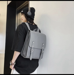 Grey minimalist vintage faux leather backpack shown worn by a model in a side view