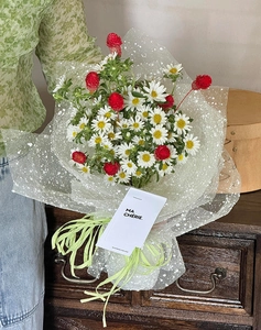 Detail of white daisy bouquet with red buds wrapped in elegant polka dot mesh gauze