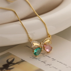 Macro view of gold butterfly pendant with green and pink gemstones and sparkling zircons
