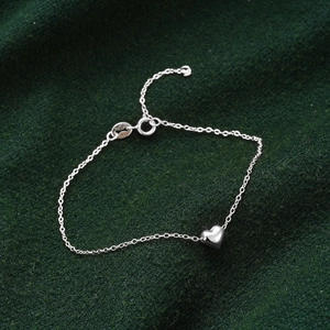 Close-up of S925 sterling silver heart bracelet on dark green velvet background