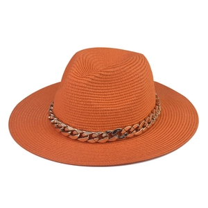 Detailed straw weave texture on an orange fedora hat featuring a chunky gold chain band