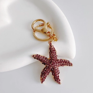 Detail of starfish keychain with purple rhinestones on a white ceramic plate