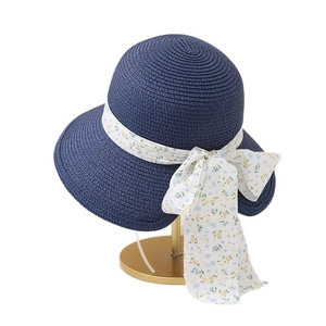 Chapeau de soleil bleu marine en paille avec ruban fleuri sur un support doré