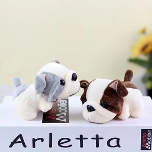 Plush puppy toy keychains in white, gray, and brown on a decorative book