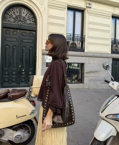 Street style view of a pale yellow pleated maxi skirt paired with a brown shoulder bag