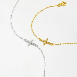 Macro detail of gold and silver cross bracelets with zircon inlays on white background
