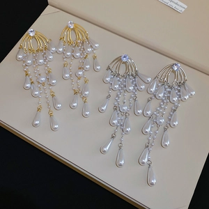 Detail of elegant tassel earrings with teardrop pearls and cubic zirconia in gold and silver