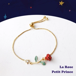 Golden rose bracelet with red flower and star charm on a celestial star background