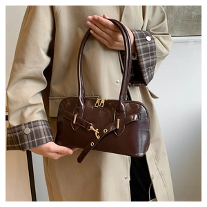 Detail of dark brown oil wax leather shell bag featuring elegant golden metal hardware