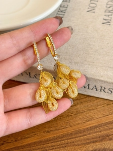 Macro shot of gold leaf tassel earrings with hollow mesh craft and sparkling zircons