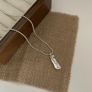 Detail of silver S925 sterling silver ball chain necklace with abstract lava pendant