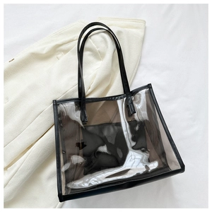 Detail view of a smoke gray PVC tote bag with black leather straps and inner pouch