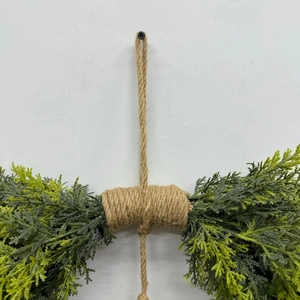 Detail of Christmas wreath featuring realistic cedar branches and a rustic twine hanger