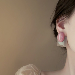 Detail of model wearing pink and gray geometric resin drop earrings in a soft studio setting