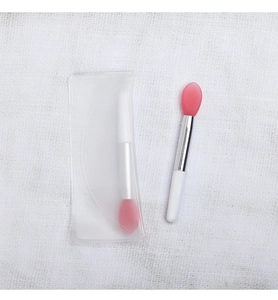Pink silicone lip scrub brush with silver ferrule and white handle in clear pouch