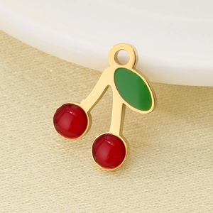 Close-up of a golden cherry pendant with red and green enamel on a white plate