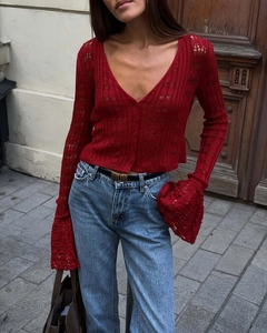 Detail of dark red knit cardigan showing hollow crochet pattern and flared cuffs