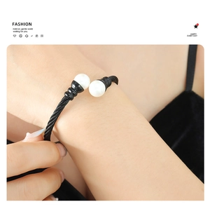 Close-up of black twisted cable bracelet with white pearl end caps on model's wrist