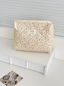 Détail d'une pochette matelassée en velours côtelé à fleurs avec fermeture éclair