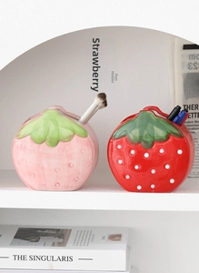 Detail of pink and red strawberry ceramic holders for pens and makeup brushes