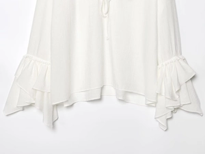 Detail van de ruchezoom en gestructureerde stof op deze witte blouse met V-hals voor dames