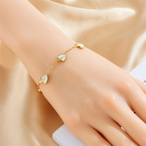Golden stainless steel leaf bracelet for women with white leaf charms on silk background