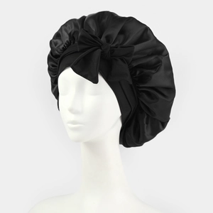 Black satin sleep cap with bow detail on mannequin head showing elastic band and texture