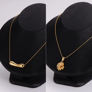 Minimalist geometric stainless steel necklace set in gold finish on black display stand